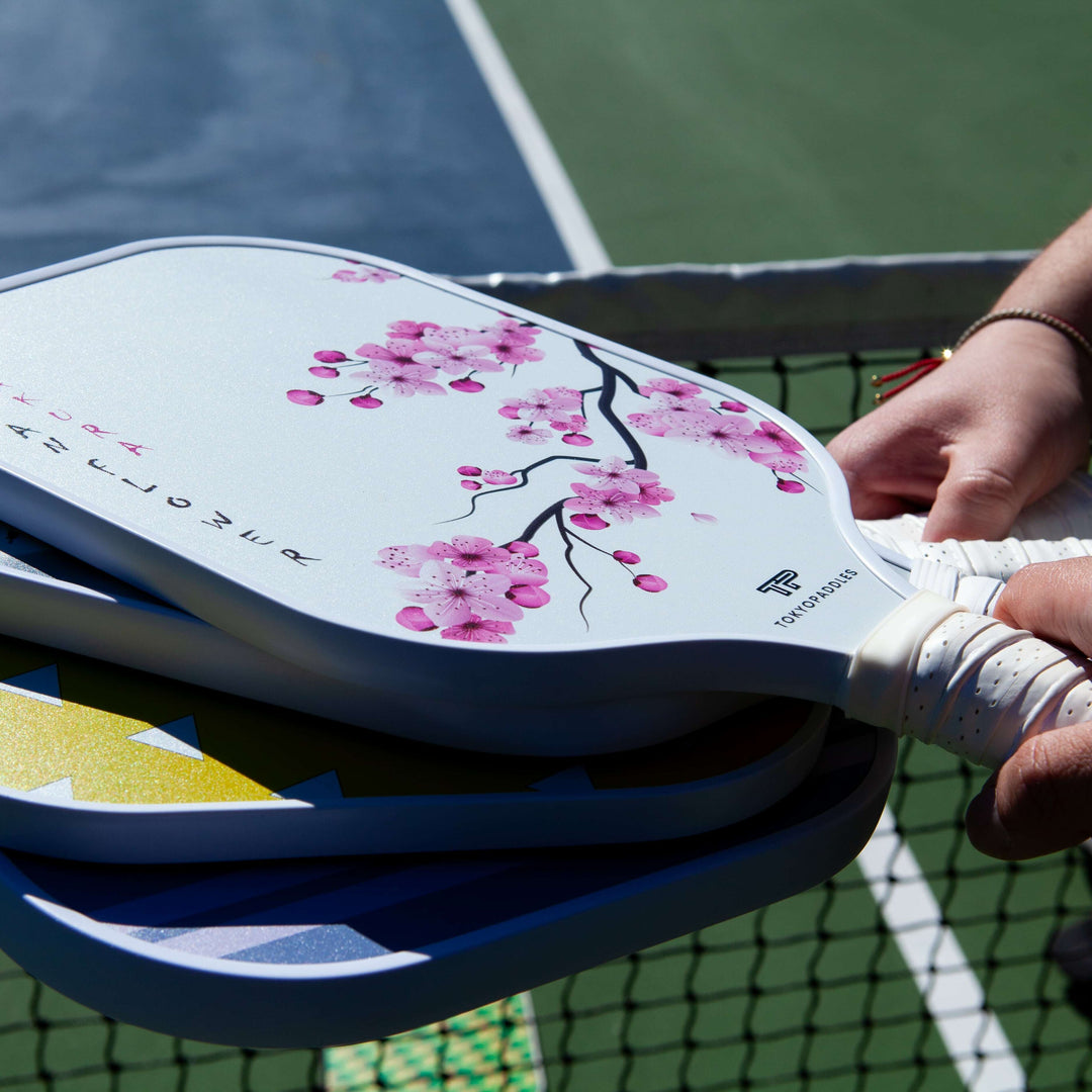 A colorful and detailed image displaying a collection of various types of pickleball paddles, each one standing apart by its design and characteristics. The paddles stand upright, their different shap